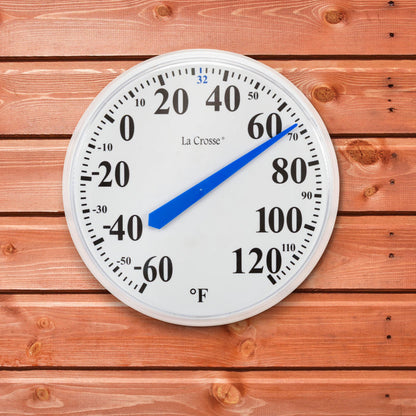 The 104-114A 13.5-inch dial thermometer with key hider, displaying the white dial with black numbers in degrees Fahrenheit from minus 60 to 120 degrees and a blue pointer highlighting freezing at 32 degrees shown hanging on a cedar color board wall or shed reading 67 degrees
