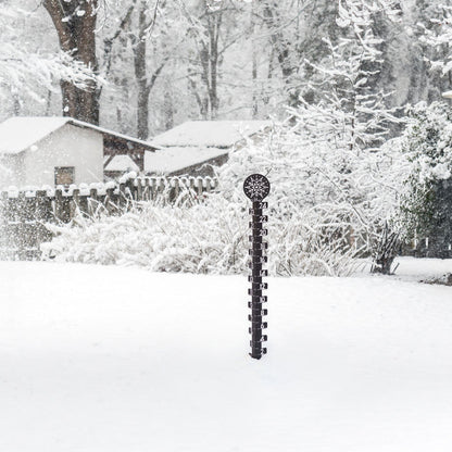 Lifstyle image of a snowy backyard with snow covered trrees, fencing, and house in the background with the 139-4686 Metal snowgague in the foreground