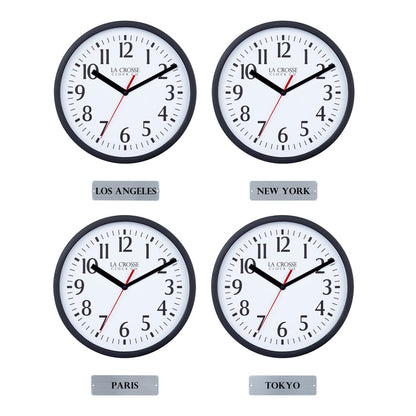 Head-on image of the 404-3020B-4TZ Four Pack 8-inch Basic Wall Clock with City Plaques showing all four clocks. The clocks feature black frames with white dials, black numbers, black hour and minute hands, and a red second hand. Beneath each clock is a small rectangular plaque labeling a city: “Los Angeles,” “New York,” “Paris,” and “Tokyo,” indicating different time zones.