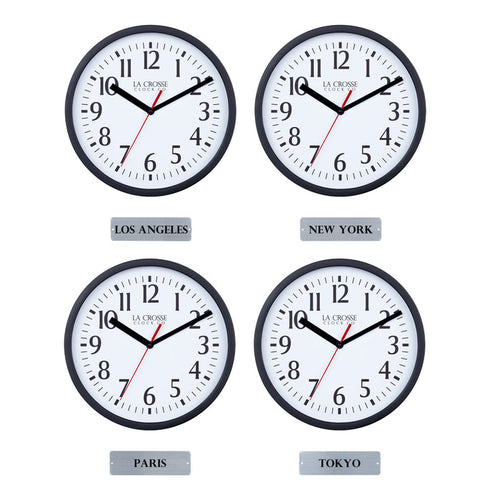 Head-on image of the 404-3020B-4TZ Four Pack 8-inch Basic Wall Clock with City Plaques showing all four clocks. The clocks feature black frames with white dials, black numbers, black hour and minute hands, and a red second hand. Beneath each clock is a small rectangular plaque labeling a city: “Los Angeles,” “New York,” “Paris,” and “Tokyo,” indicating different time zones.