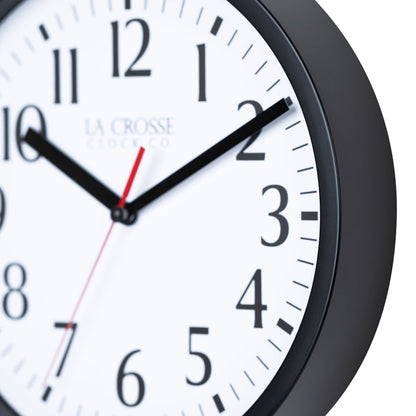 Close-up image of the frame detail of the 404-3020B-4TZ Four Pack 8-inch Basic Wall Clock with City Plaques. The clock features a black frame with a white clock face, black numbers, black hour and minute hands, and a red second hand.
