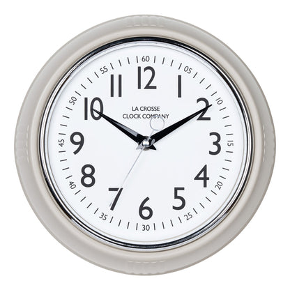 Head-on image of the 404-3024TP 9.5-inch Diner Clock – Taupe. The clock features a retro-style taupe frame with a white dial, chrome bezel, black numbers and minute markings, black metal hands, and a silver second hand.