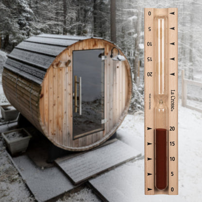 918-631 Sauna Hourglass Timer showing the wood casing, glass tube, and red sand with markings 0 to 20 minutes and the La Crosse logo superimposed over a lifestyle image of an outdoor Sauna in winter