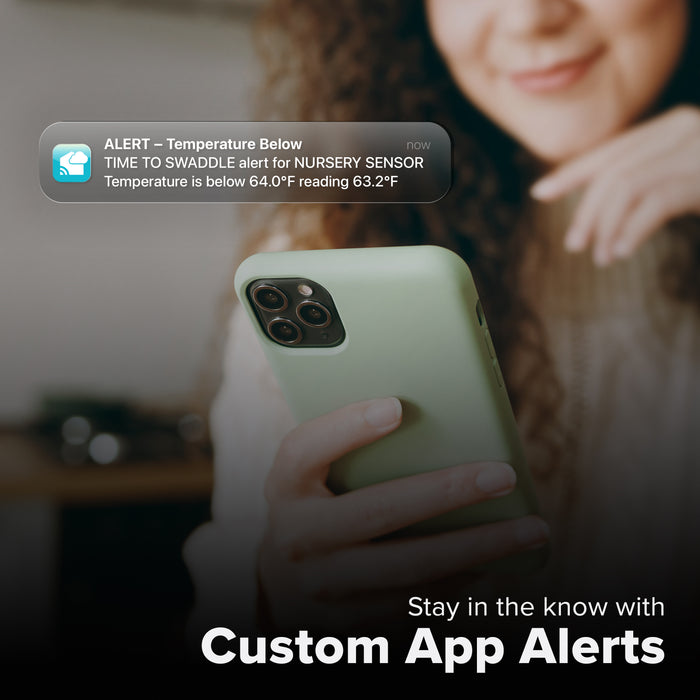 La Crosse Technology Alert and Monitoring system with a female looking at her smartphone receiving an alert for the indoor temperature dropping below set parameters of a custom alert for an interior temperature and humidity sensor with text that says stay in the know with Custom Alerts