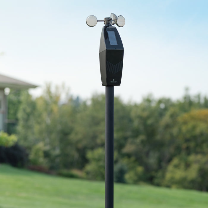 LTV-W3 Glide Pro wind Sensor works with the bridge gateway or wi-fi connected weather station for alert and monitoring shown in a backyard with green grass and green trees in the background the sensor is mounted on a black pole in the foreground