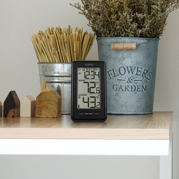 ws-9160 Digital thermometer on a shelf with decorative items including a metal bucket labeled 'Flowers & Garden'.